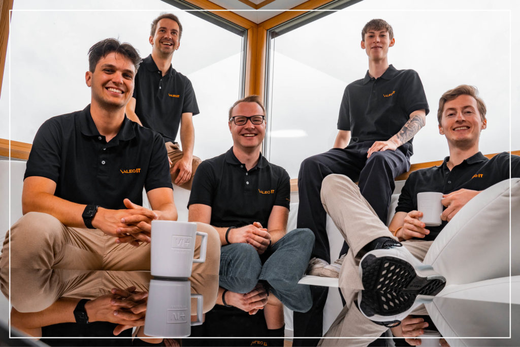 Fünfe junge Männer am Sofa in schwarzen Shirt